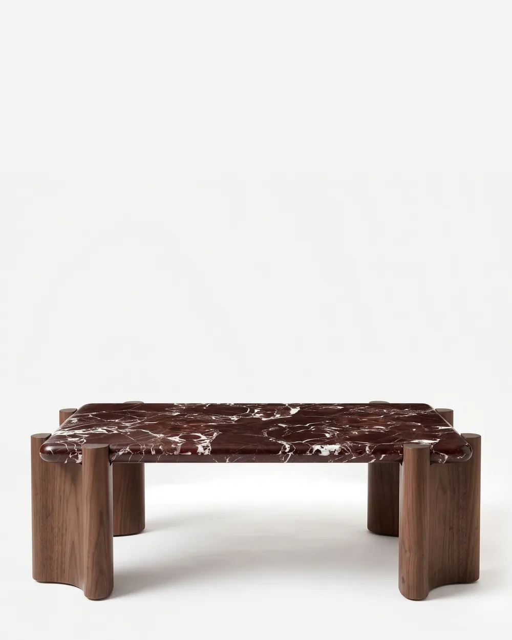 Draven Coffee Table coffee table — walnut wood sculpted column legs with a scalloped profile, set just beyond the corners of a rectangular top in Rosso…