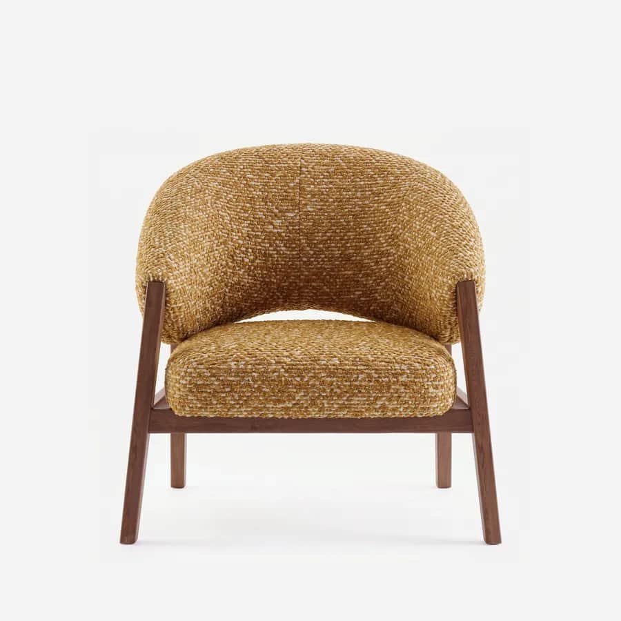 Vale Lounge Chair lounge chair — walnut wood frame with angled side supports and a low stretcher, upholstered in a textured bouclé fabric, cradling a…