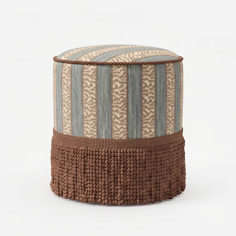 Niko Pouf pouf — round, fully upholstered pouf in a striped pattern fabric, with a corded top edge and a deep looped fringe skirt wrap…