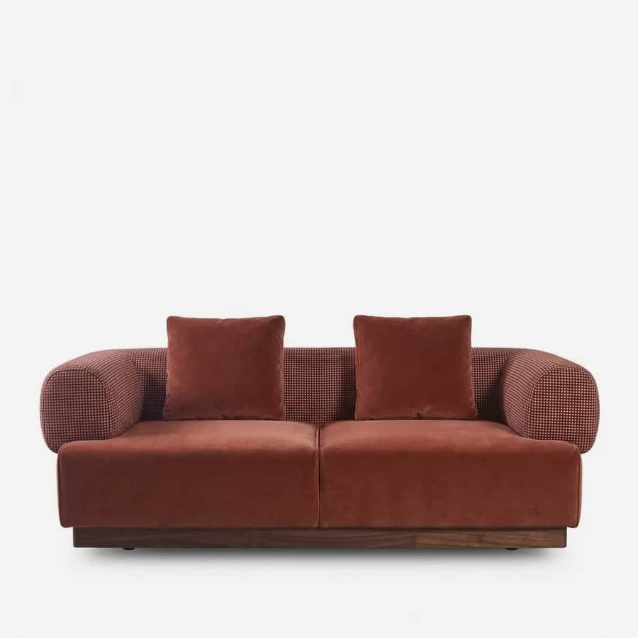 Lume Sofa sofa — walnut wood plinth base under a two-seat body in pattern fabric, with velvet seat and back cushions and rounded bolst…