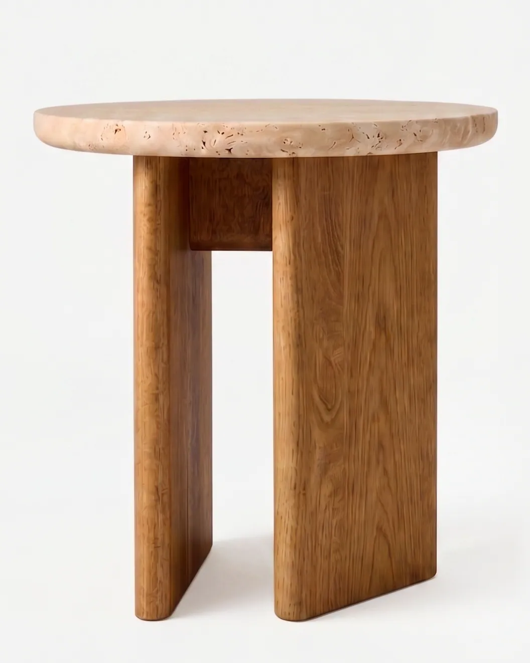Tessa Side Table side table — iroko wood base of flat slabs set in a cross, carrying a round beige travertine top with a softly rounded edge and vi…