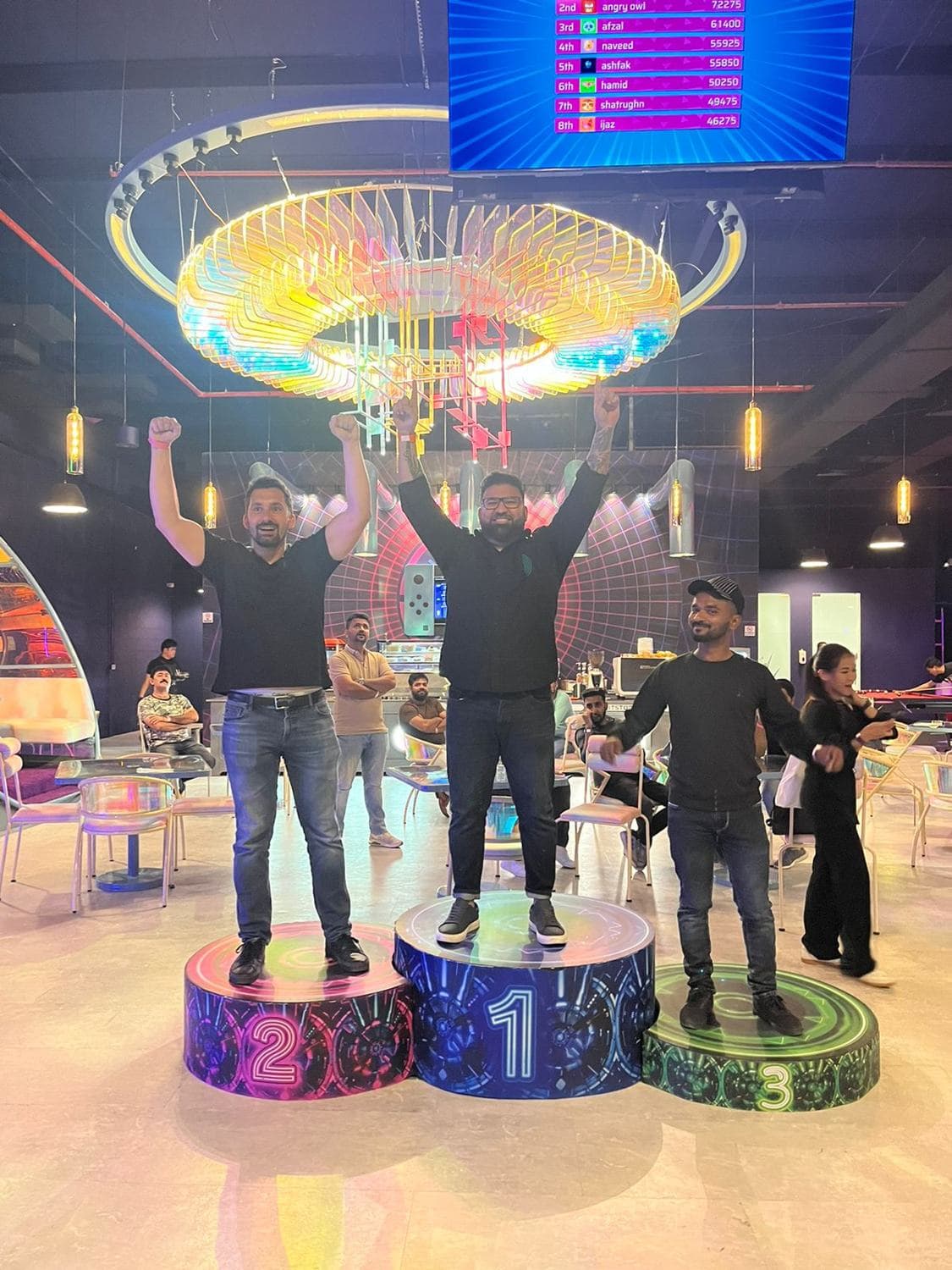 Three colleagues celebrating on a podium at a games night