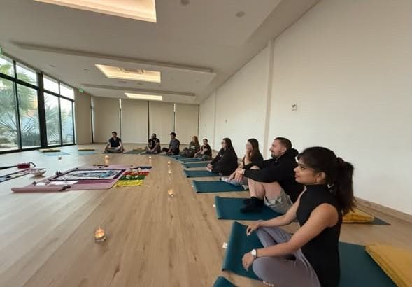 The team meditating together on mats in a bright studio