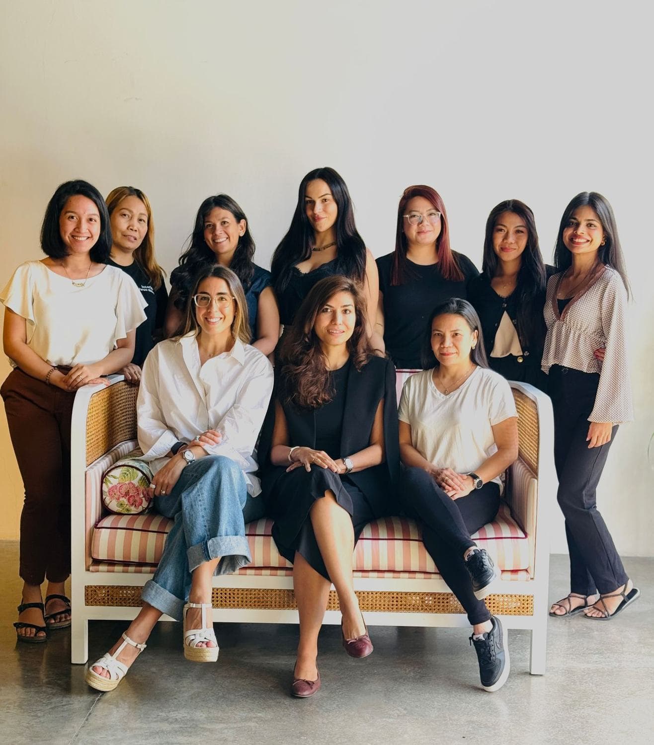 The women of the studio team seated and standing around a striped sofa